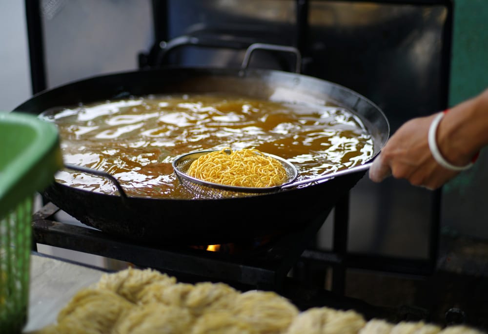 A chef frying noodles in a large wok, which creates the used cooking oil that Renova helps restaurants in Texas manage without frustration.
